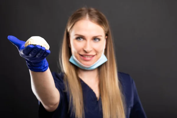 Enfoque selectivo de la hermosa dentista femenina sosteniendo dentur —  Fotos de Stock