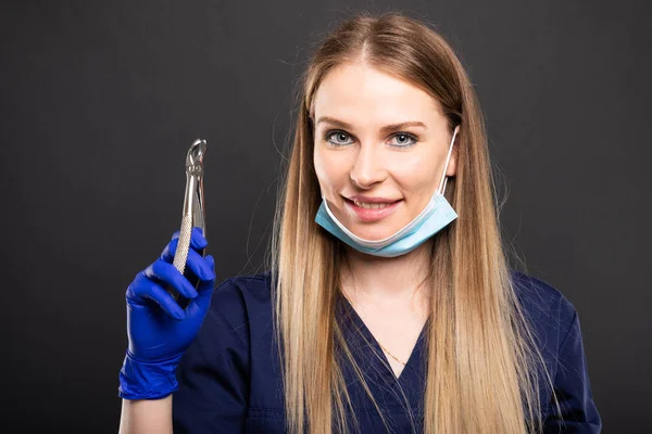 Beautiful female dentist using face mask holding too — Stock Photo, Image
