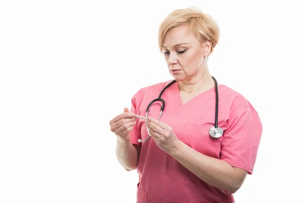 温度計を保持しているピンクのスクラブを着て魅力的な女性看護師 — ストック写真