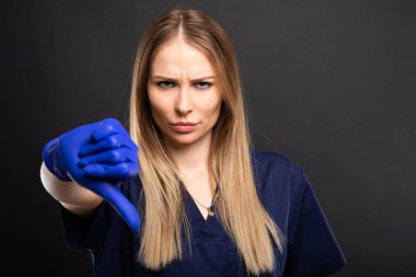 Güzel kadın dişçi giyen scrubs gösterilen dow başparmak