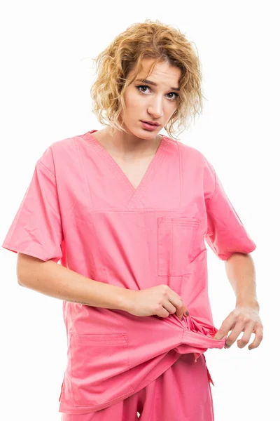 Portrait of young nurse wearing pink scrub showing empty pocket — Stok fotoğraf
