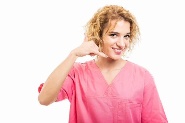 Portrait of nurse wearing pink scrub showing calling gesture — 图库照片