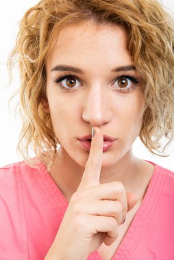 Close-up of nurse wearing pink scrub making silence gesture