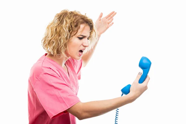 Side view of nurse wearing pink scrub yelling at telephone recei — Stockfoto