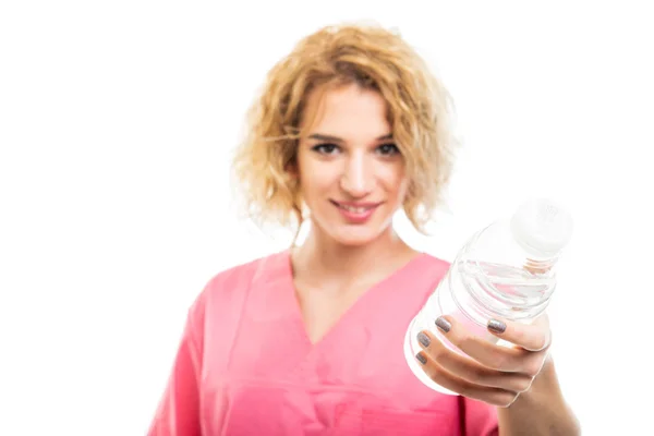 Selective focus of nurse wearing pink scrub holding bottle of wa — ストック写真