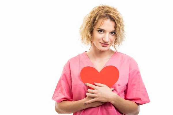 Portrait of nurse wearing pink scrub holding red heart — ストック写真