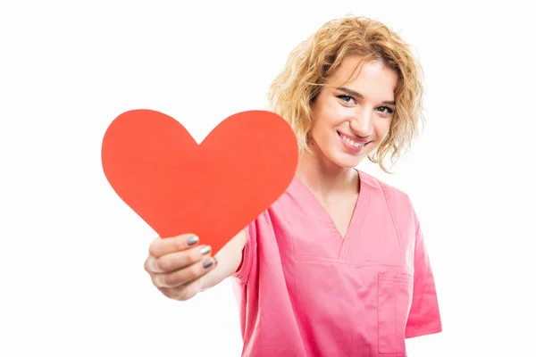 Porträt einer Krankenschwester, die ein rosafarbenes Peeling trägt und rotes Herz schenkt — Stockfoto