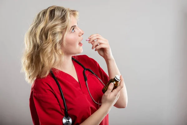 Retrato Una Enfermera Vestida Rojo Tomando Una Pastilla Sobre Fondo — Foto de Stock