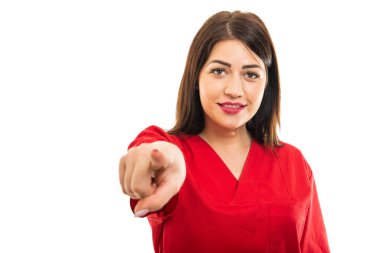 Önlük giymiş güzel genç doktorun portresi beyaz arka planda izole edilmiş fotokopi alanı reklamlarıyla kamerayı işaret ediyor.