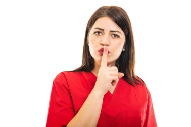 Doktor önlüğü giymiş portresi beyaz arka planda izole edilmiş sessizlik hareketi yapıyor.