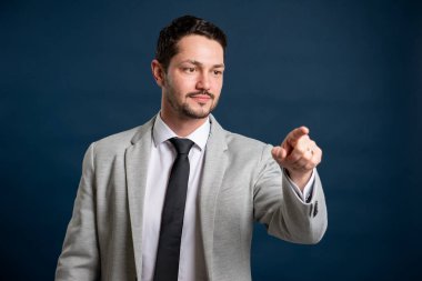 İş portresi genç yakışıklı erkek giysi kravatı dokunmatik ekran kullanarak ve mavi arka planda gülümseyerek