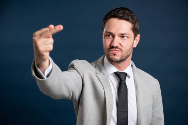 İş portresi genç yakışıklı erkek mavi arka planda müstehcen hareketler sergiliyor