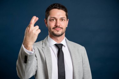 İş portresi genç yakışıklı erkek işaret parmaklarını mavi arka planda fotokopi alanı reklam alanında gösteriyor.