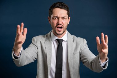 İş portresi genç erkek mavi arka planda çığlık atıyor