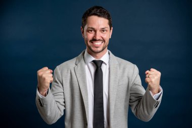 İş portresi genç yakışıklı erkek mavi arka planda zafer jesti yapıyor