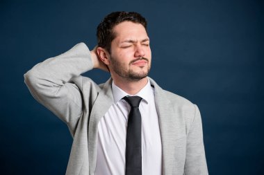 İş portresi genç erkek mavi arka planda sırt ağrısı jesti yapıyor