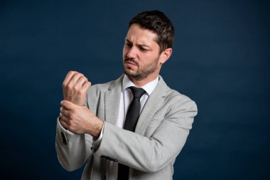 İş portresi genç erkek bilek ağrısı jesti yapıyor mavi arka planda fotokopi alanı reklam alanı ile