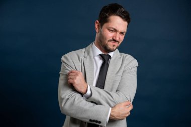 İş portresi genç erkek dirsek ağrısı jesti mavi arka planda fotokopi alanı reklam alanı ile