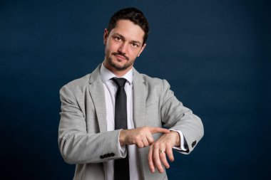 İş portresi genç yakışıklı erkek geç saatte mavi arka planda fotokopi alanı reklam alanında el hareketi yapıyor.