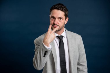 İş adamı genç yakışıklı erkek, mavi arka planda fotokopi alanı reklam alanıyla gözlerimin içine bakıyor.