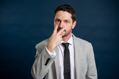 İş adamı genç yakışıklı erkek, mavi arka planda fotokopi alanı reklam alanıyla gözlerimin içine bakıyor.