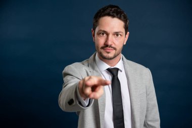 İş adamı genç yakışıklı erkek, senin mavi arka planda fotokopi alanı reklam alanındaki hareketlerini izliyor.