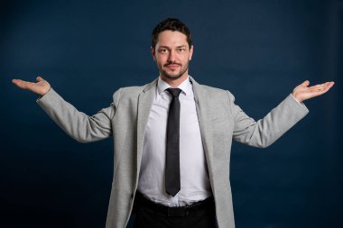 İş dünyasından genç yakışıklı erkek elinde fotokopi alanı ile mavi arka planda fotokopi alanı reklam alanı tutuyor.