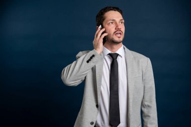 İş portresi genç erkek telefonda konuşuyor mavi arka planda fotokopi alanı reklam alanı ile