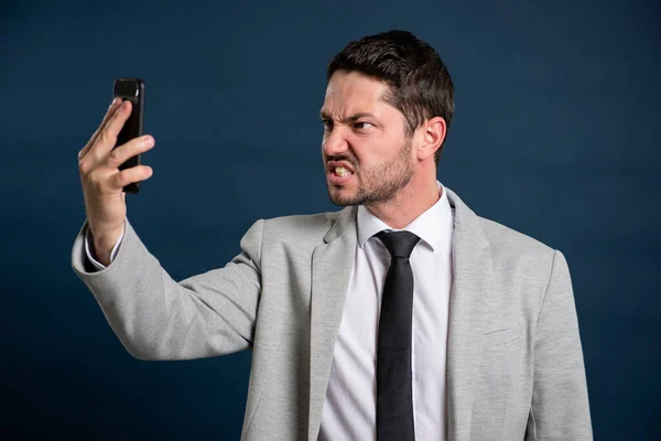 Retrato Hombre Joven Negocios Mirando Loco Teléfono Sobre Fondo Azul —  Fotos de Stock