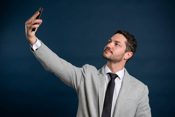 Portrait of business young male taking selfie on background
