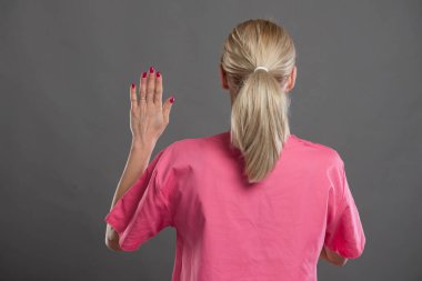 Genç ve çekici kadın hemşirenin gri arka plan üzerine yemin edişinin arkası.