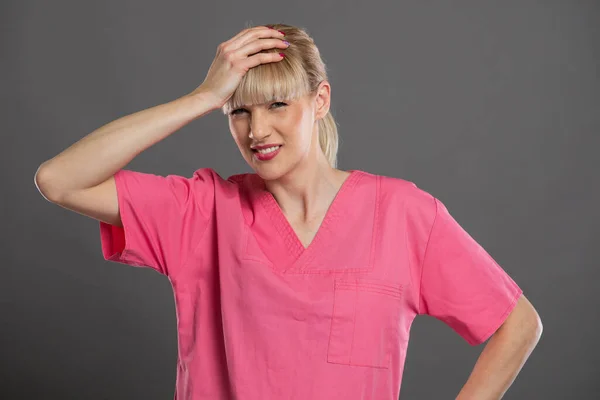 若い魅力的な女性看護師の肖像グレーの背景に問題ジェスチャーを作る — ストック写真