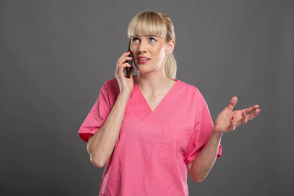Portret Van Jonge Aantrekkelijke Vrouwelijke Verpleegster Praten Smartphone Grijze Achtergrond — Stockfoto
