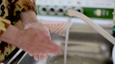 Sarı ceketli kız Coronavirus sırasında ellerini sabunla iyice yıkıyor. Yakın plan.