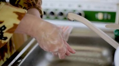 Sarı ceketli kız Coronavirus sırasında ellerini sabunla iyice yıkıyor. Yakın plan.