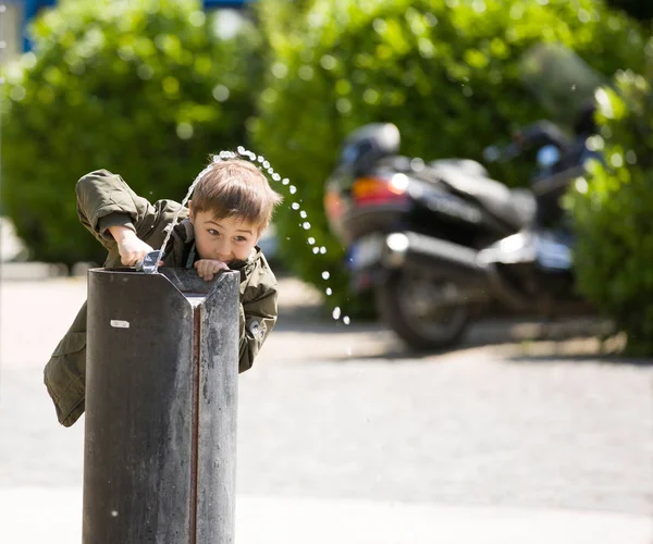 Petit garçon joue avec l'eau de fontaine publique dans le parc — Photo