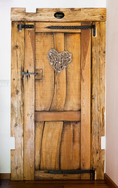 Rustikale Holztür mit gehämmerter Eisenverstärkung, herzförmigem Ornament, privat — Stockfoto