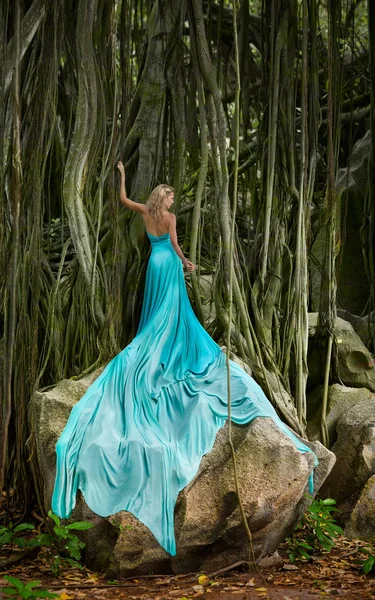 Long haired, extreme long turquoise dressed woman with strangler fig — Stock Photo, Image