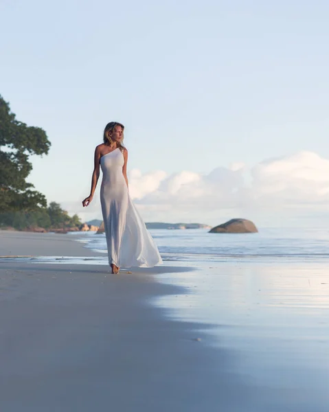 Mulher loira bonita e sexy caminha na praia tropical, vestido longo — Fotografia de Stock