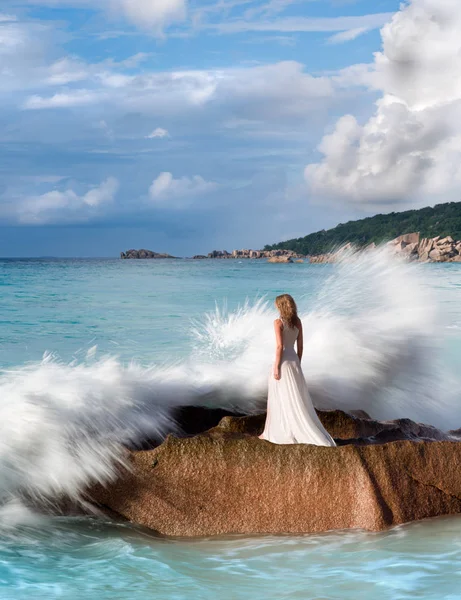 Gyönyörű nő áll, a rock, fröccsenő tenger hullámai, fehér ruhában — Stock Fotó