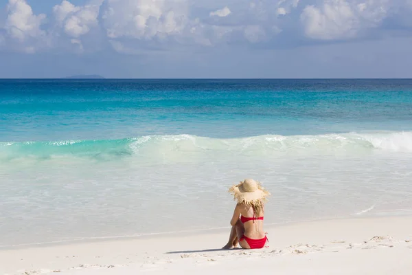 Praia tropical, água de turquise e horizonte. Mulher loira magro senta-se em maiô vermelho . — Fotografia de Stock