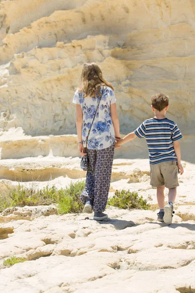 Menino e menina caminha juntos lado a lado ao ar livre, rochoso Malta deserto — Fotografia de Stock