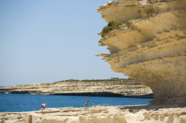 Malta vahşi kayalıklarla ve ıssız sahil, deniz yanında oynayan çocuklar