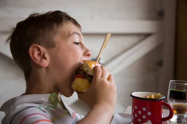 Młody chłopak zjada duże hamburger — Zdjęcie stockowe
