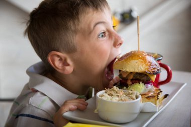 Genç bir büyük hamburger ısırmaya hazırlar