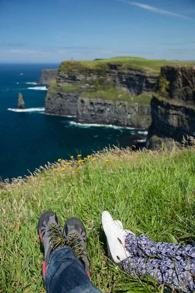 莫赫悬崖, 北爱尔兰海洋海岸线, 阳光明媚的夏季景观, 休息的脚的人 图库照片