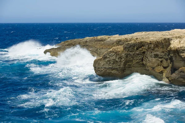 Malta, Gozo-saaren rannikko, luonnonvaraiset aallot ja kivet, sininen taivas - merihorisontti — kuvapankkivalokuva