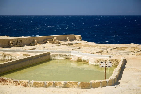 Vieilles salières abandonnées, signe d'avertissement rouillé et horizon au-dessus de la mer sur l'île de Gozo, Malte — Photo
