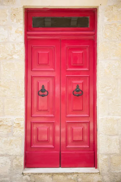 Red painted old wooden door with black iron handle in medieval city street — Stock Photo, Image