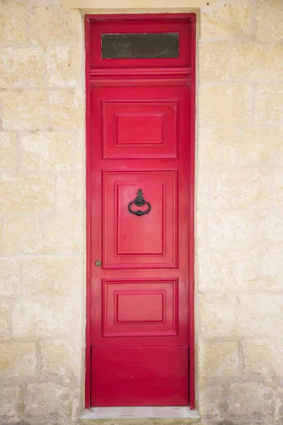 Red painted old wooden door with black iron handle in medieval city street — Stock Photo, Image